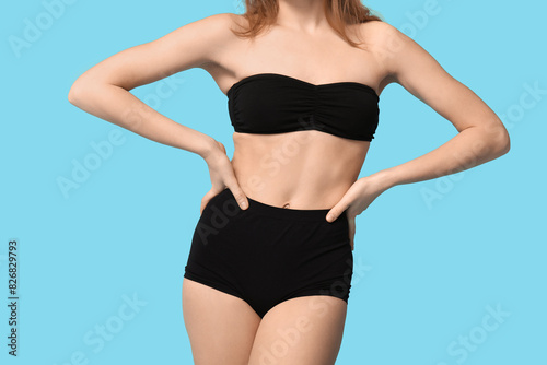 Sexy young woman in black underwear on blue background