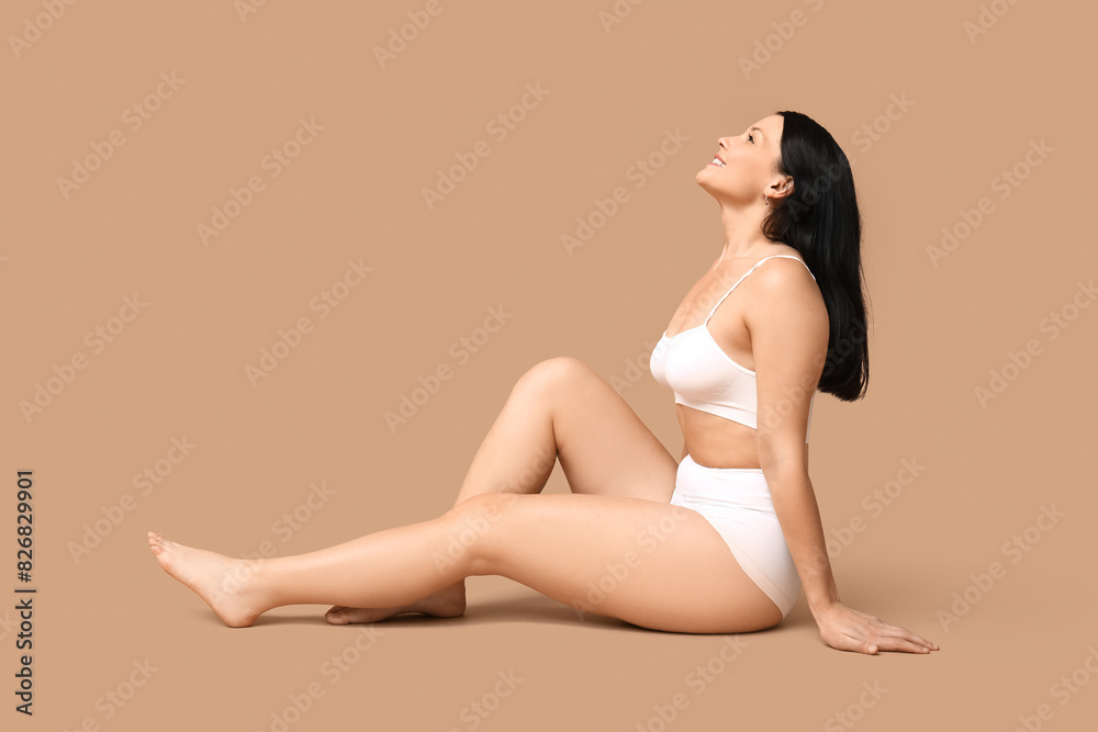 Body positive woman in underwear sitting on beige background
