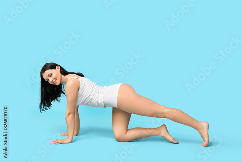 Body positive woman in underwear posing on blue background