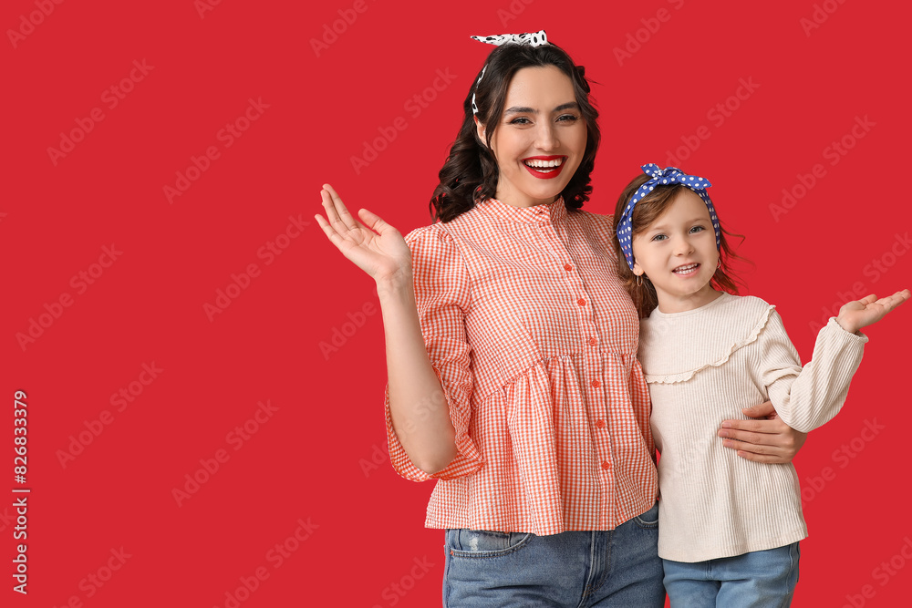 Beautiful pin-up woman and her daughter on red background