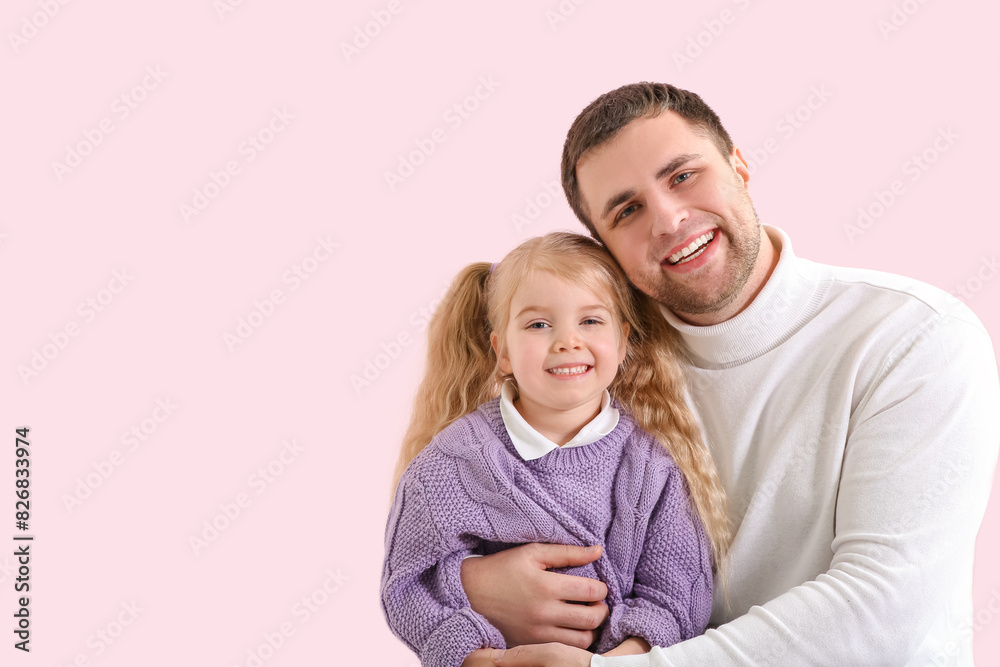 Happy father and his cute little daughter on pink background