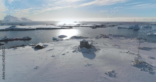 Antarctica polar station buildings on ocean bay coastline. Winter landscape. Snow-covered rocky land. Untouched wilderness of Antarctic nature, mountains in background. Explore, travel to South Pole