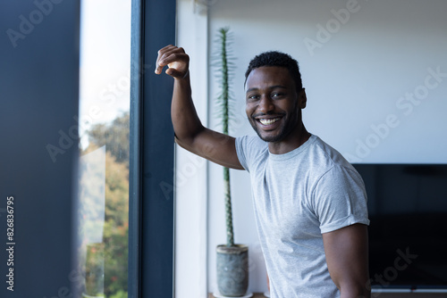 An African American man at home, leaning on window frame, smiling photo