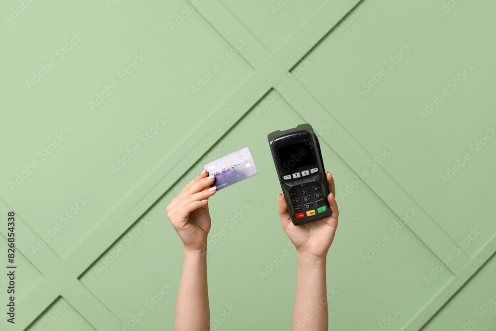 Female hands with credit card and payment terminal on green background Female hands with credit card and payment terminal on green background