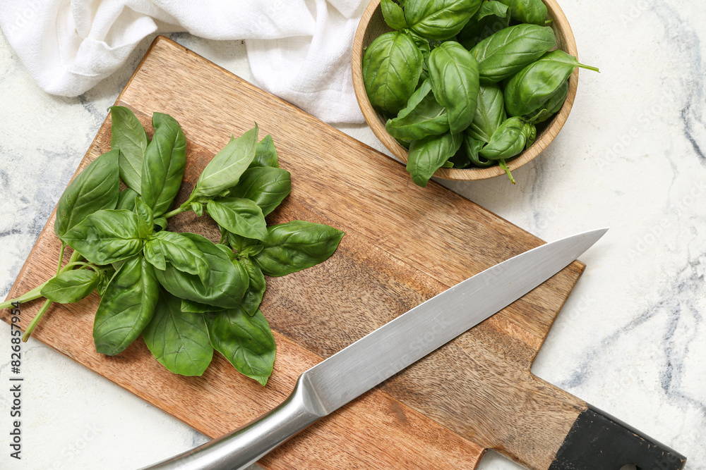 Wooden bowl and board with fresh green basil leaves on white background Wooden bowl and board with fresh green basil leaves on white background