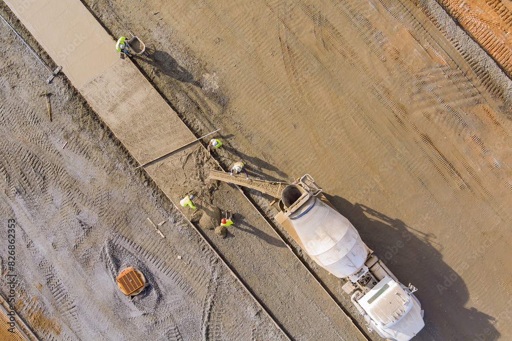 Obraz premium Concrete is poured from mixer truck for construction of pedestrian walkway by masonry workers