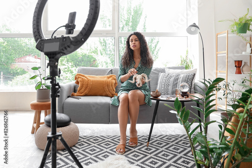 Young African-American witch with goat skull recording video at home photo