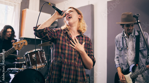 People, band and music practice with singer, microphone and electric guitar for concert rehearsal at home. Musician group, vocal training and recording song, track and audio with team work in garage photo