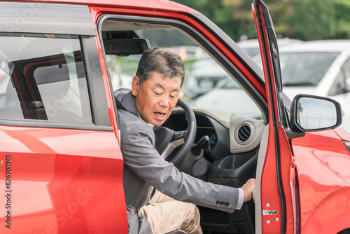 駐車場で自動車のドアを開けてバックする高齢者ドライバーの男性（ぶつける・驚く・焦る・うっかり） 