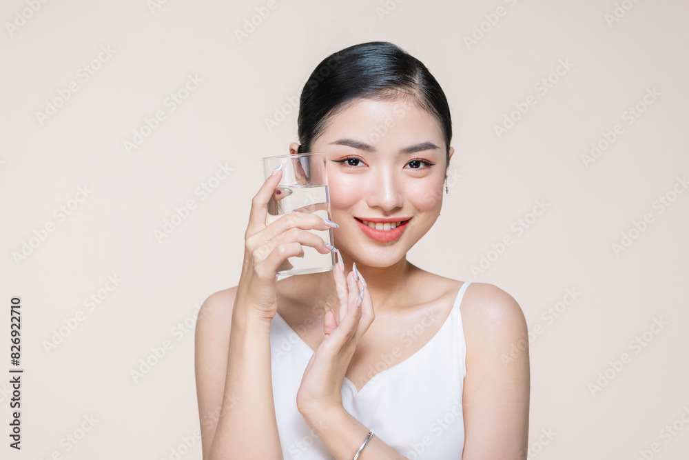 Young adult woman holds a glass of water in her hand near face Young adult woman holds a glass of water in her hand near face