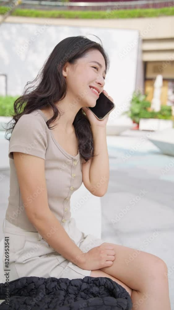 Vertical pretty young asian businesswoman talking on the mobile phone smile at summer day Vertical pretty young asian businesswoman talking on the mobile phone smile at summer day
