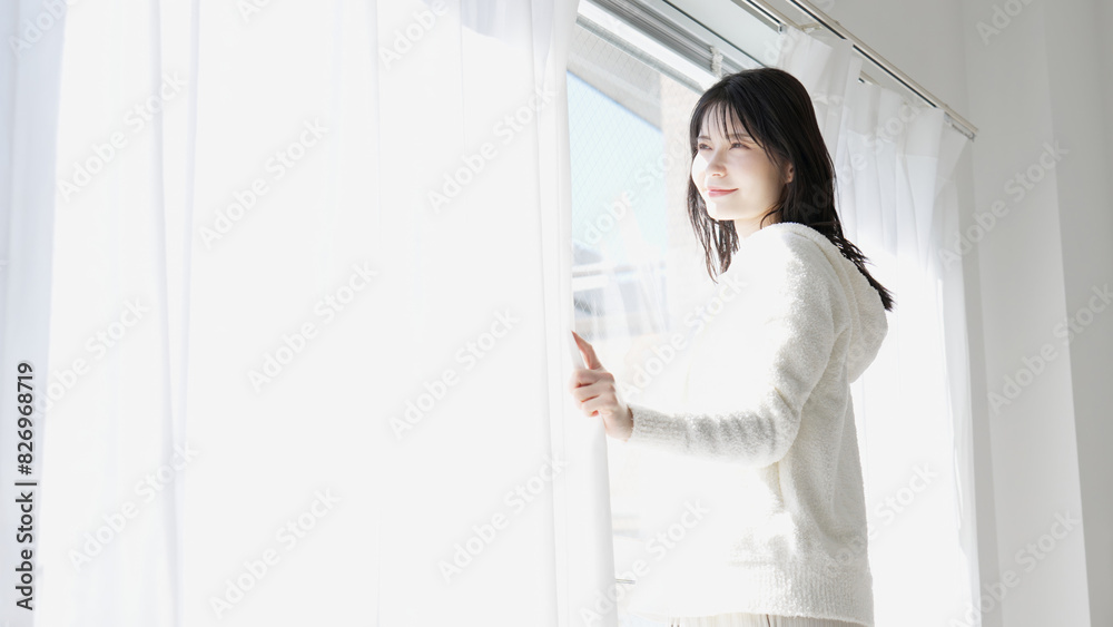 朝、カーテンを開ける女性 朝、カーテンを開ける女性