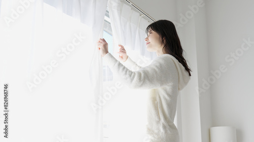 Fotografía 朝、カーテンを開ける女性