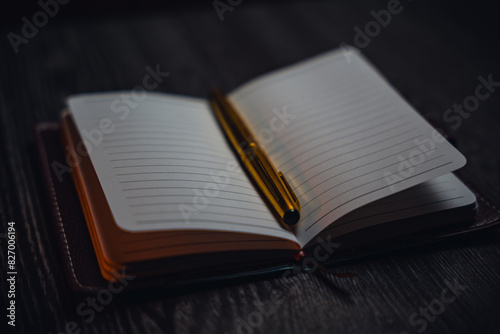 A notebook with a gold pen on the table in the candlelight