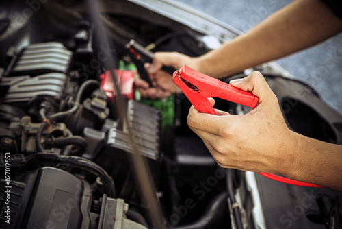 Hand car mechanic holding car booster cables for jump start car for empty battery dead and low voltage power problem or fix and service maintenance accident assistance engine doesn't start.
