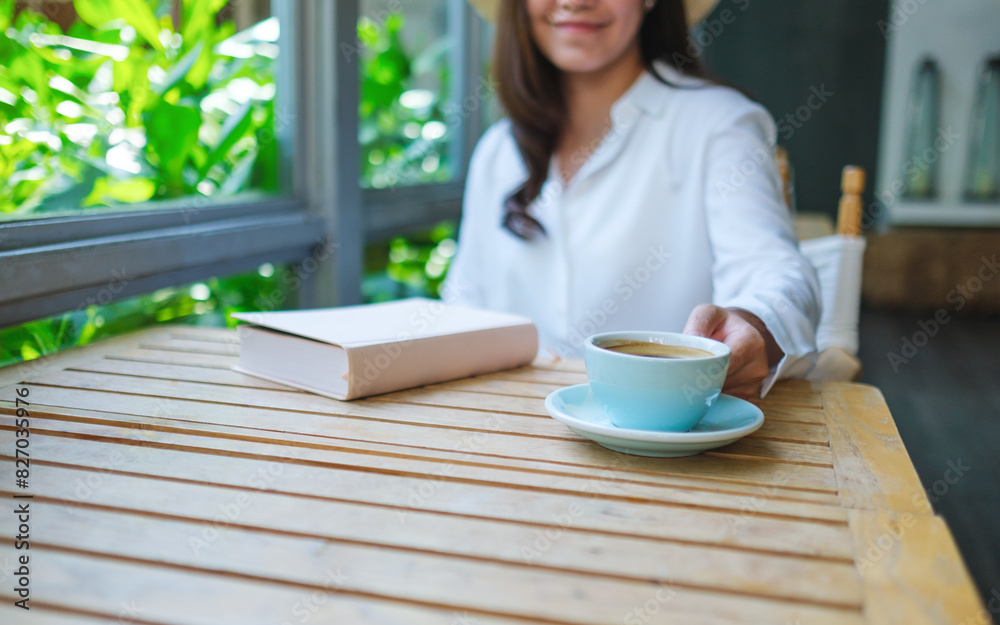 Closeup image of a woman drinking coffee with a book on table Closeup image of a woman drinking coffee with a book on table