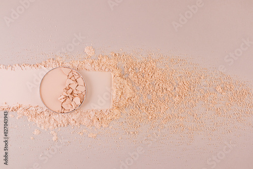 A block of compact powder in a natural tone with the texture of broken pieces stands on a swatch of powder. loose powder. A copy space. top view.