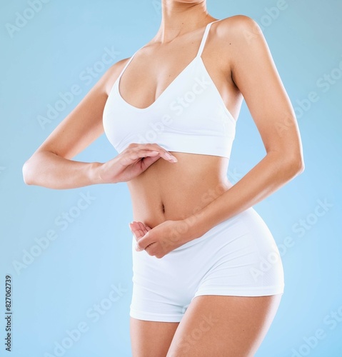 Body, woman and hands frame on stomach in studio for diet, gut health and nutrition for natural skin wellness. Underwear, abdomen and slim model lose weight for digestion isolated on blue background © peopleimages.com