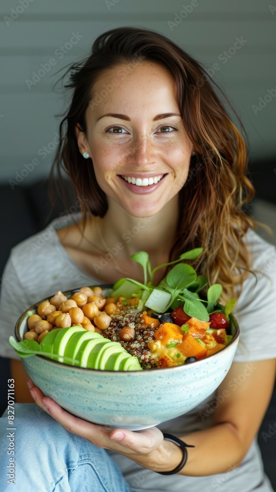 A cheerful young woman smiling while holding a bowl filled with a nutritious mixture of quinoa, avocado, chickpeas, and assorted vegetables A cheerful young woman smiling while holding a bowl filled with a nutritious mixture of quinoa, avocado, chickpeas, and assorted vegetables