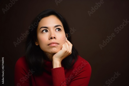 contemplative woman with hand on chin in studio