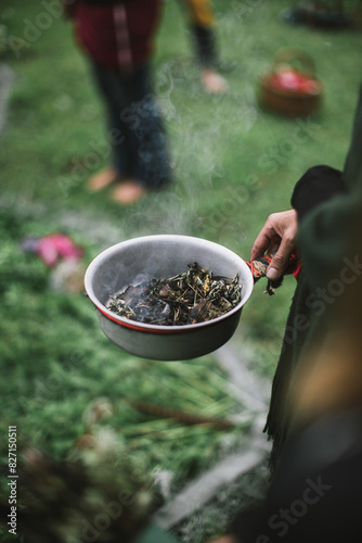 Smudging ceremony outdoors, with herbs smoking in a hand-held bowl