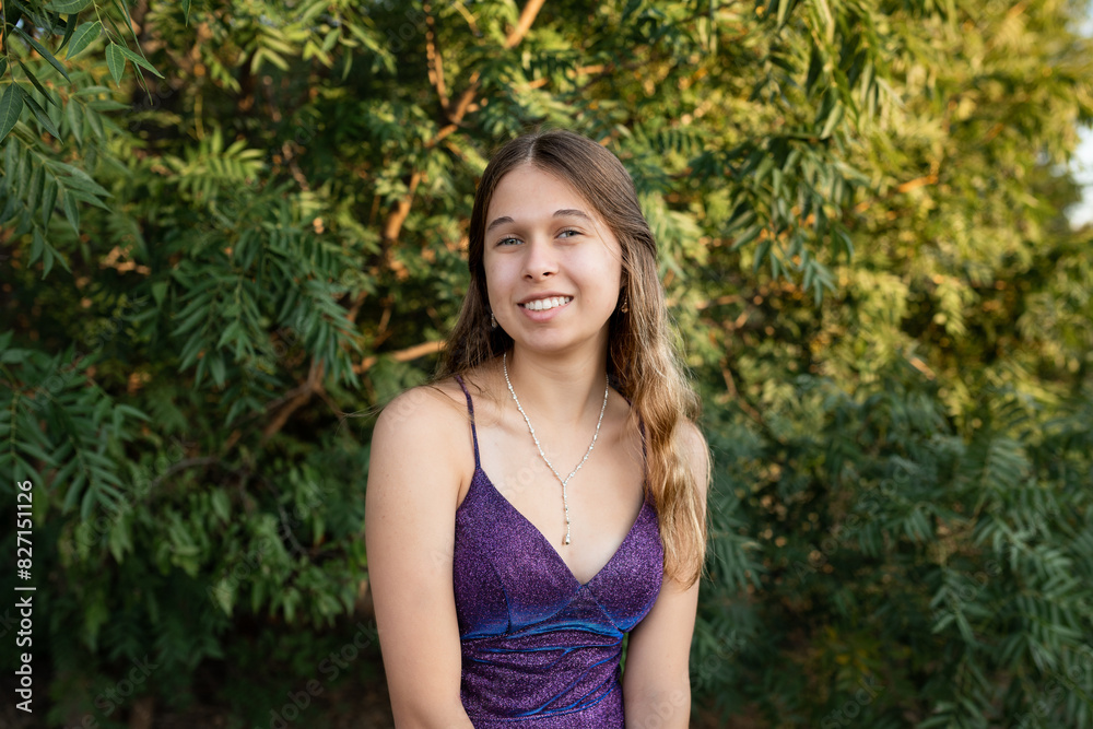 portrait of a smiling young woman in a purple dress  with trees