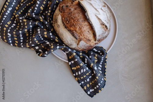 Rustic loaf of bread on a plate with a patterned cloth