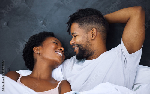 Black couple and eye contact in bed with romance for love with tender, embrace and care in morning with smile. Dating, relationship and relaxing with passion for partner with comfort or waking up.
