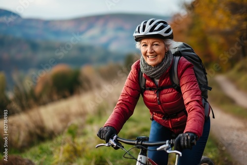 Smiling mature woman enjoys a bicycle ride through picturesque landscapes, exuding health and happiness against a vivid, autumnal background
