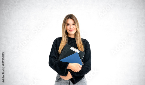 Young woman with long hair holding folders against a white backg photo