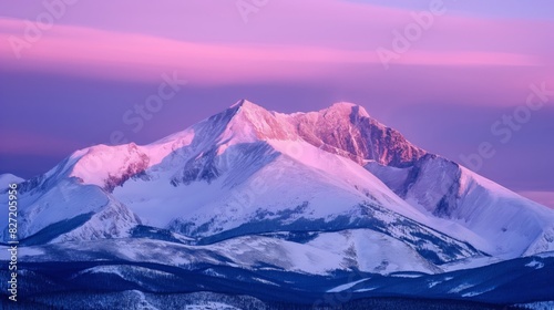Captivating photo of a snow-covered mountain peak under a soft pink alpenglow at dusk