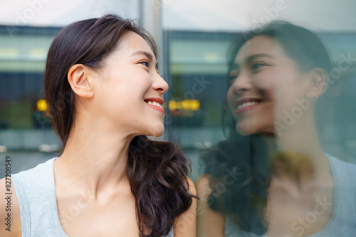 pretty young asian woman looking at her reflection in the mirror self appreciation