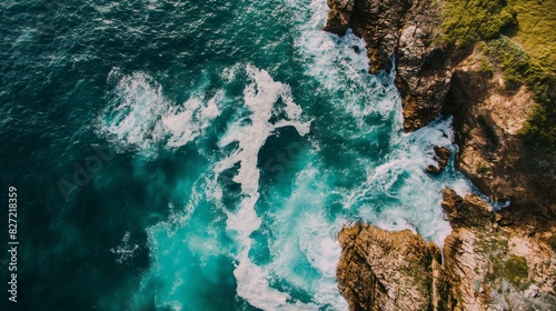 Top-down shot capturing the dynamic interface between a craggy coastline and the vibrant sea