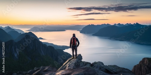 man admiring the fjord at dawn from mountain peak, norway