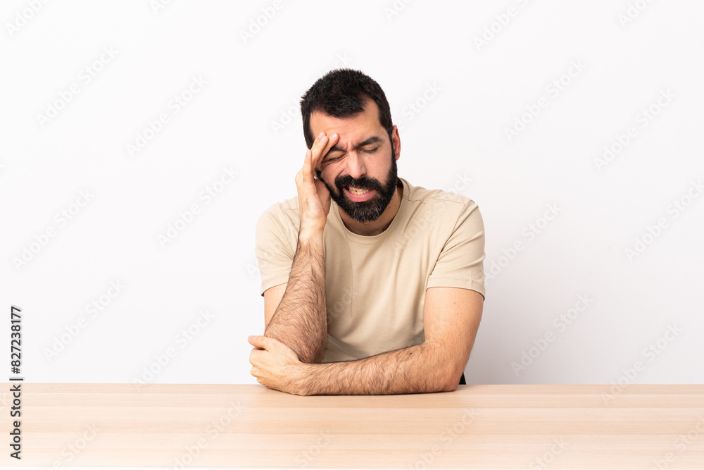 Caucasian man with beard in a table with headache. Caucasian man with beard in a table with headache.
