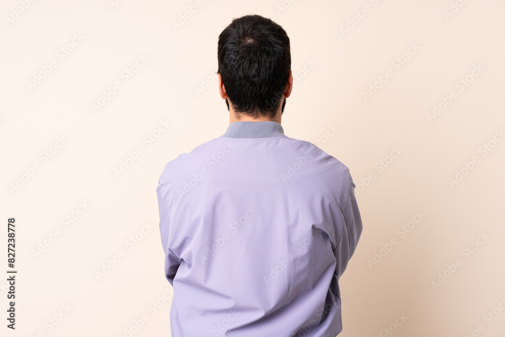 Caucasian man with beard wearing a jacket over isolated background in back position Caucasian man with beard wearing a jacket over isolated background in back position