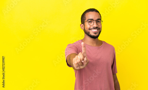 Young latin man isolated on yellow background showing and lifting a finger © luismolinero