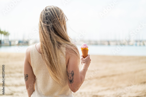Young blonde woman with a cornet ice cream at outdoors in back position photo
