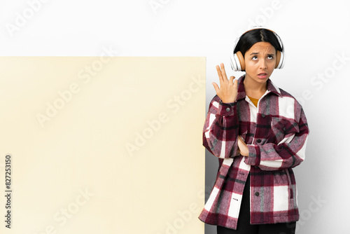 Young woman listening music with a big empty placard over isolated background with problems making suicide gesture photo