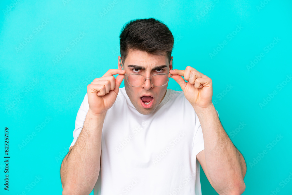 Naklejka premium Young caucasian man isolated on blue background With glasses and frustrated expression