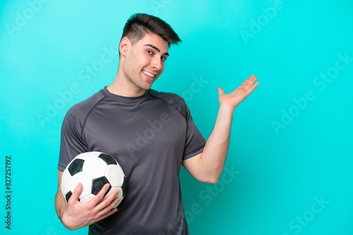 Young caucasian football player man isolated on blue background extending hands to the side for inviting to come