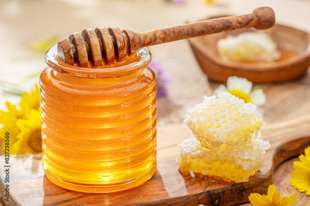 Natural organic honey in glass jar, honey dipper and honeycombs are near. Natural food background. Natural organic honey in glass jar, honey dipper and honeycombs are near. Natural food background.