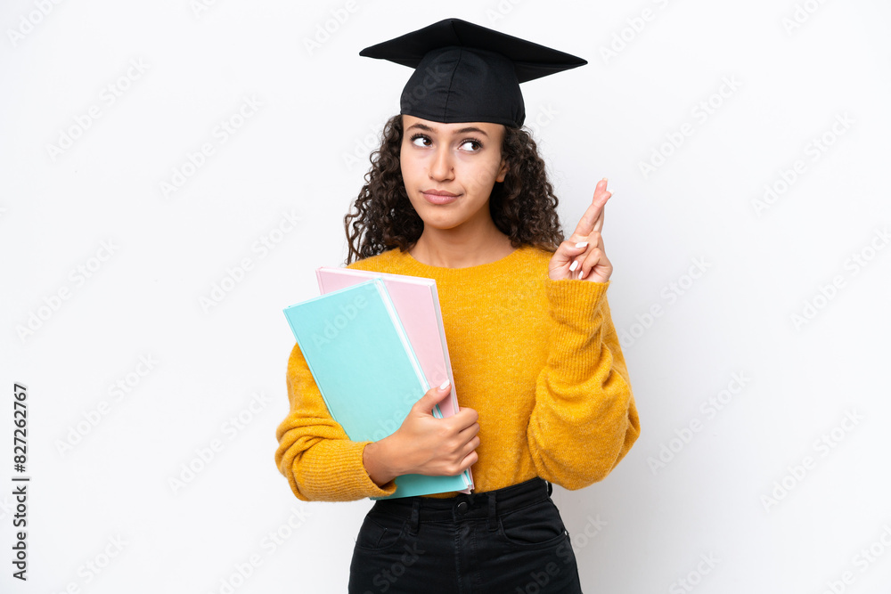 Arab university graduate woman holding books isolated on white background with fingers crossing and wishing the best Arab university graduate woman holding books isolated on white background with fingers crossing and wishing the best