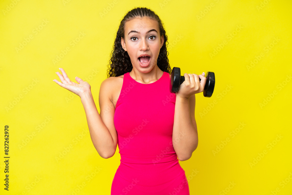 Young sport woman making weightlifting isolated on yellow background with shocked facial expression Young sport woman making weightlifting isolated on yellow background with shocked facial expression