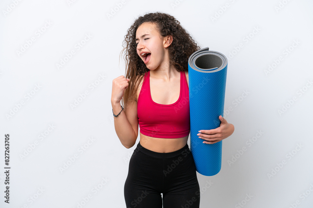 Young sport Arab woman going to yoga classes while holding a mat isolated on white background celebrating a victory Young sport Arab woman going to yoga classes while holding a mat isolated on white background celebrating a victory