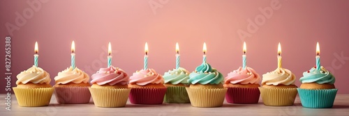 Colorful cupcakes with lit candles are displayed against a pink background, indicating an indoor celebration event marking of joy and celebrating. banner with free space