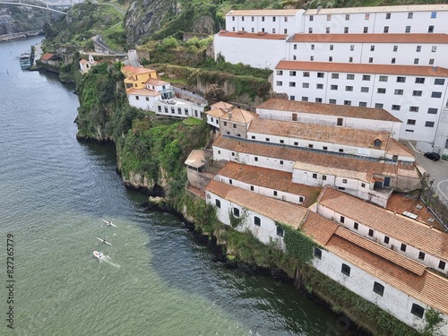 Typical buildings in Porto with white walls and red roofs, Douro river downstairs, view from one of the bridges in Porto, ships on the river and green nature