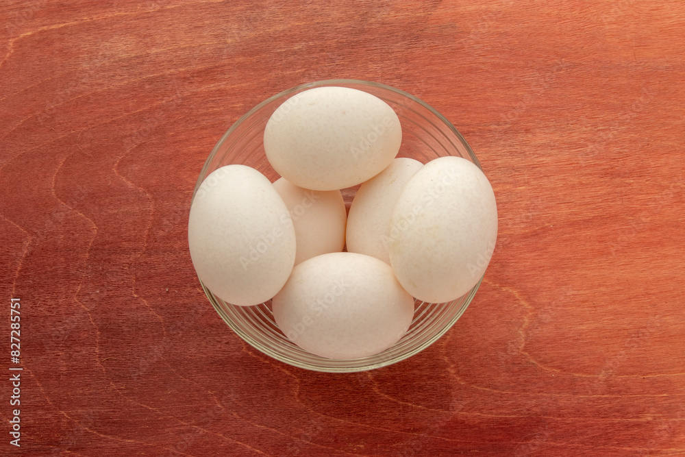Top view of fresh eggs in a bowl on a wooden table Top view of fresh eggs in a bowl on a wooden table