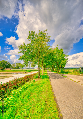 Big clouds almost touching the country road in a rural landscape in The Netherlands.