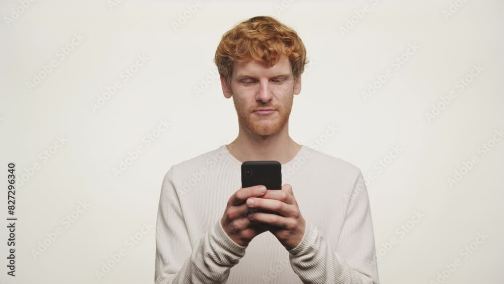 Young Man with Red Hair Texting on Smartphone Young Man with Red Hair Texting on Smartphone